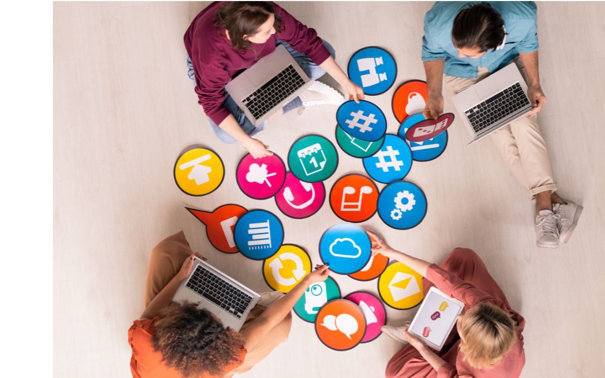 A group of people sitting together at a work table looking through illustrations of digital icons.